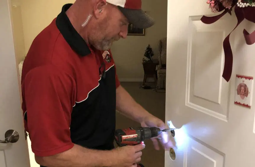 Security Technician Installs Access Control Lock on Apartment Door