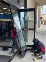 Commercial door technicians install new storefront doors for a local business