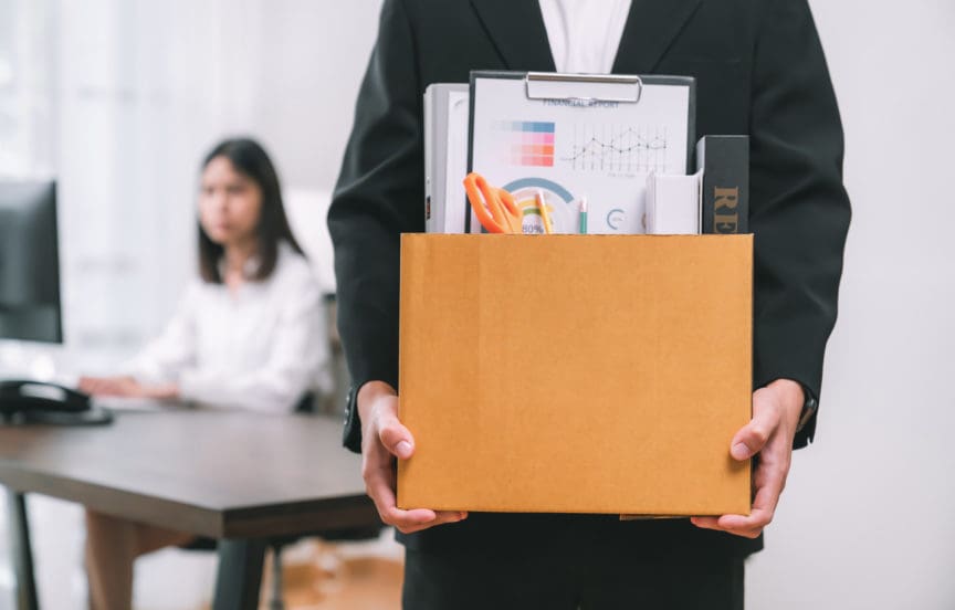 Businessman packaging and holding brown cardboard box with documents and personal office supplies because fired from work.