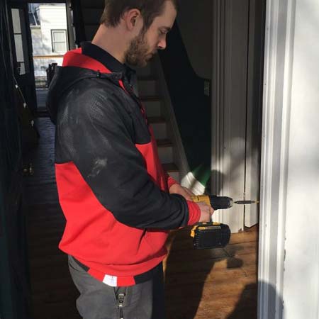 Door security systems specialist drills hole for access control card reader installation near Hartford, CT