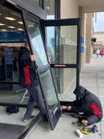 Commercial door technicians install new storefront doors for a local business