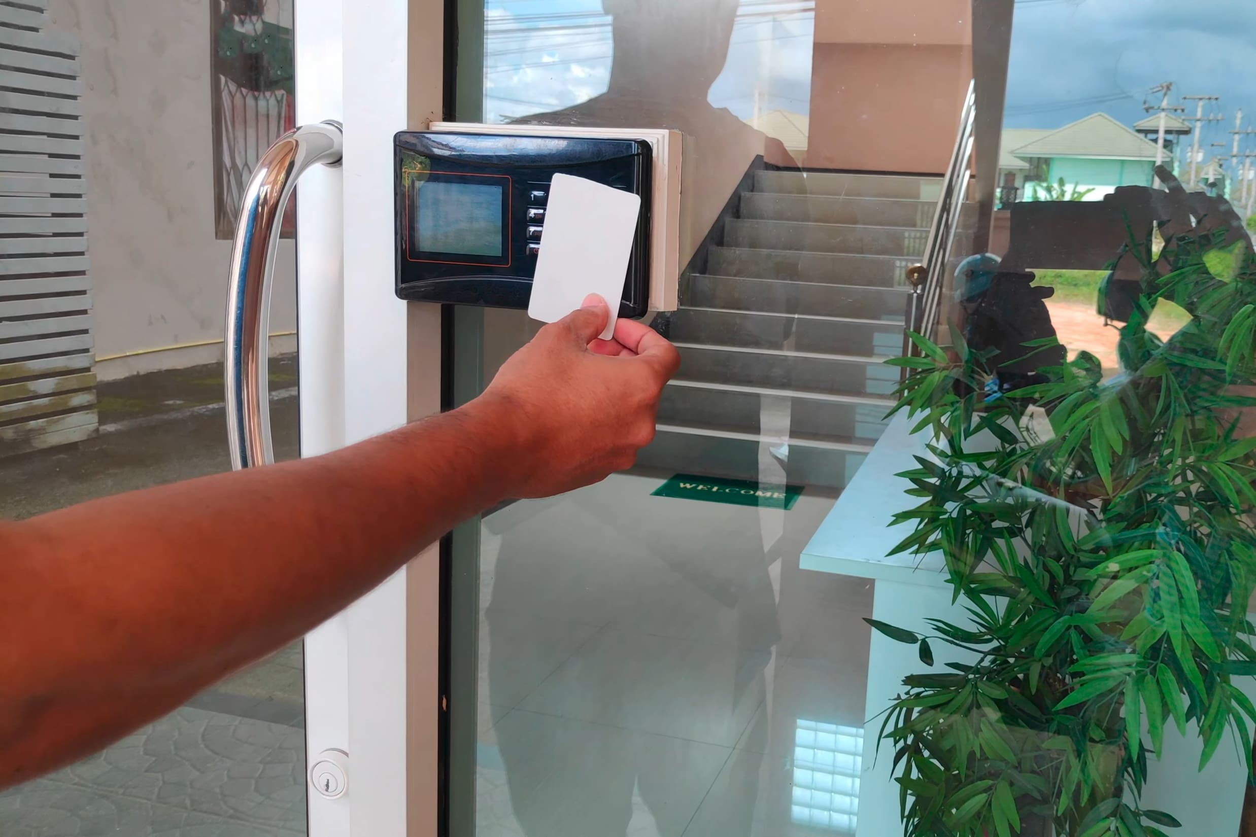 an employee waves an ID card in front of an alarm lock access control system